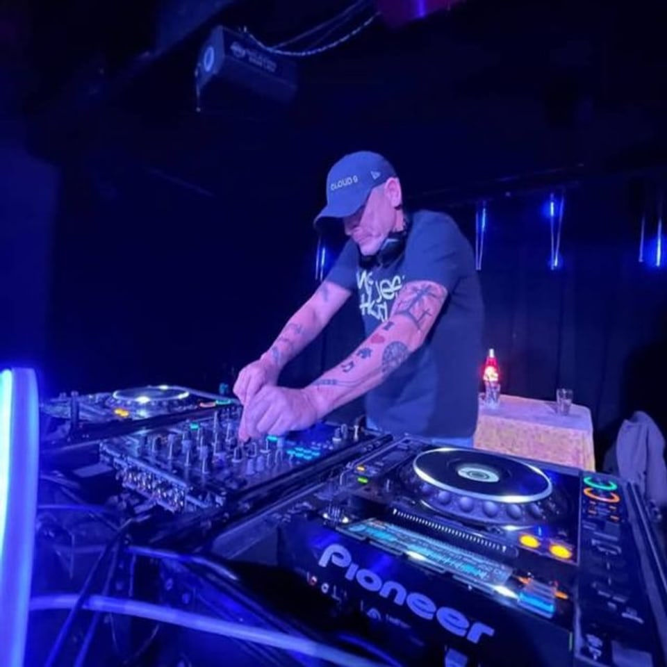 Josh Halsel performing as DJ Cloud 9 behind Pioneer decks under blue and violet stage lighting